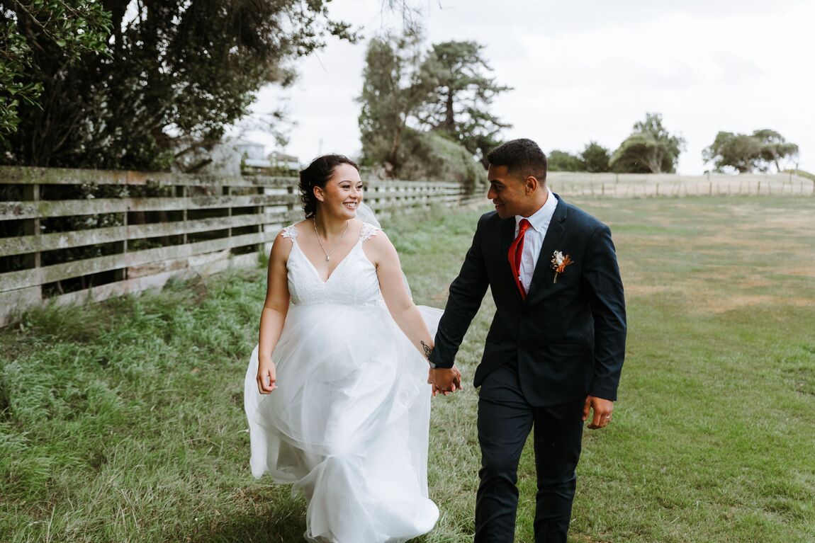 Couple holding hands and smiling while walking across a lawn