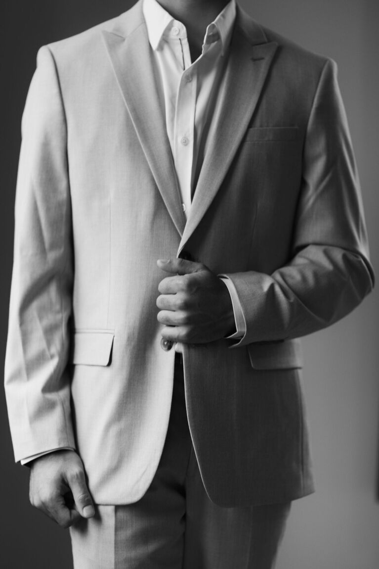 Groom adjusting his suit jacket, black and white