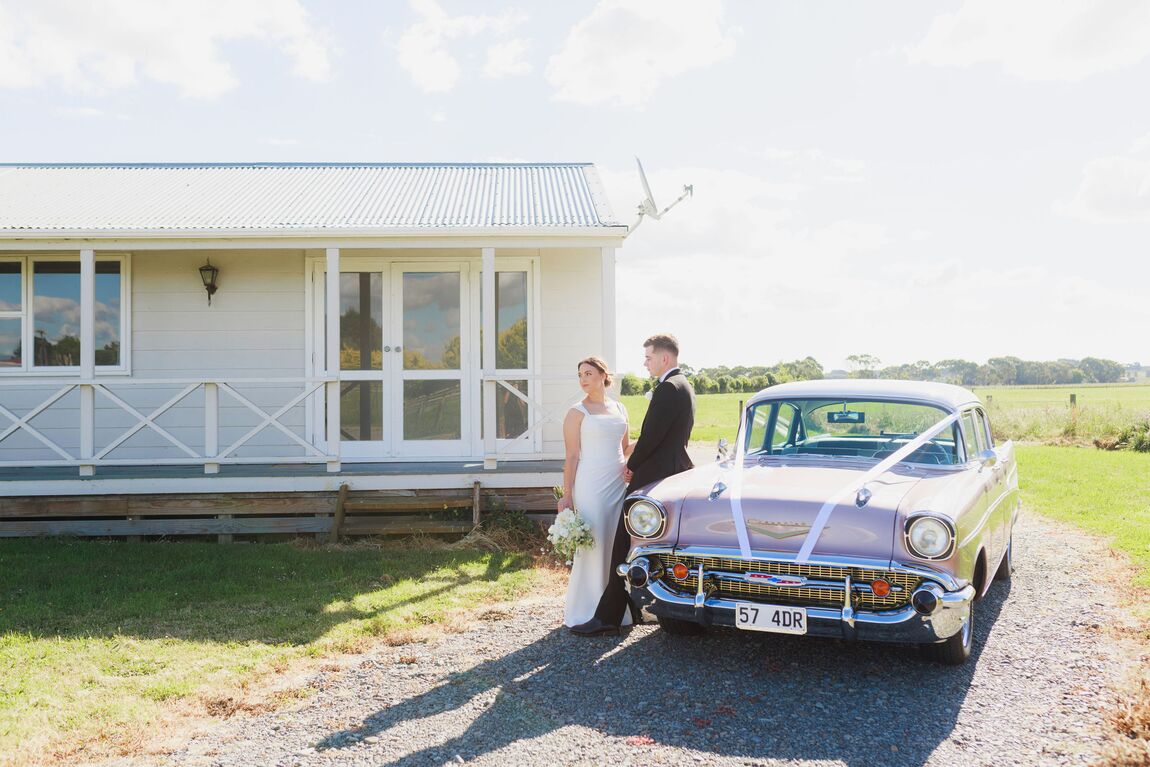 Bride and groom beside a vintage car